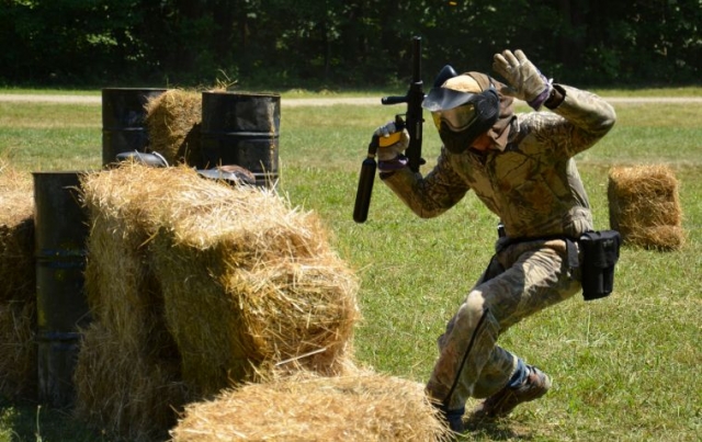 hombre con las manos levantadas mientras juega al paintball